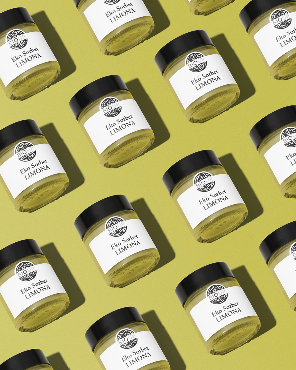 Ułożone pod kątem słoiki z ekologicznym sorbetem cytrynowym na jednolitym, oliwkowym tle, prezentujące produkt w powtarzalnym wzorze.