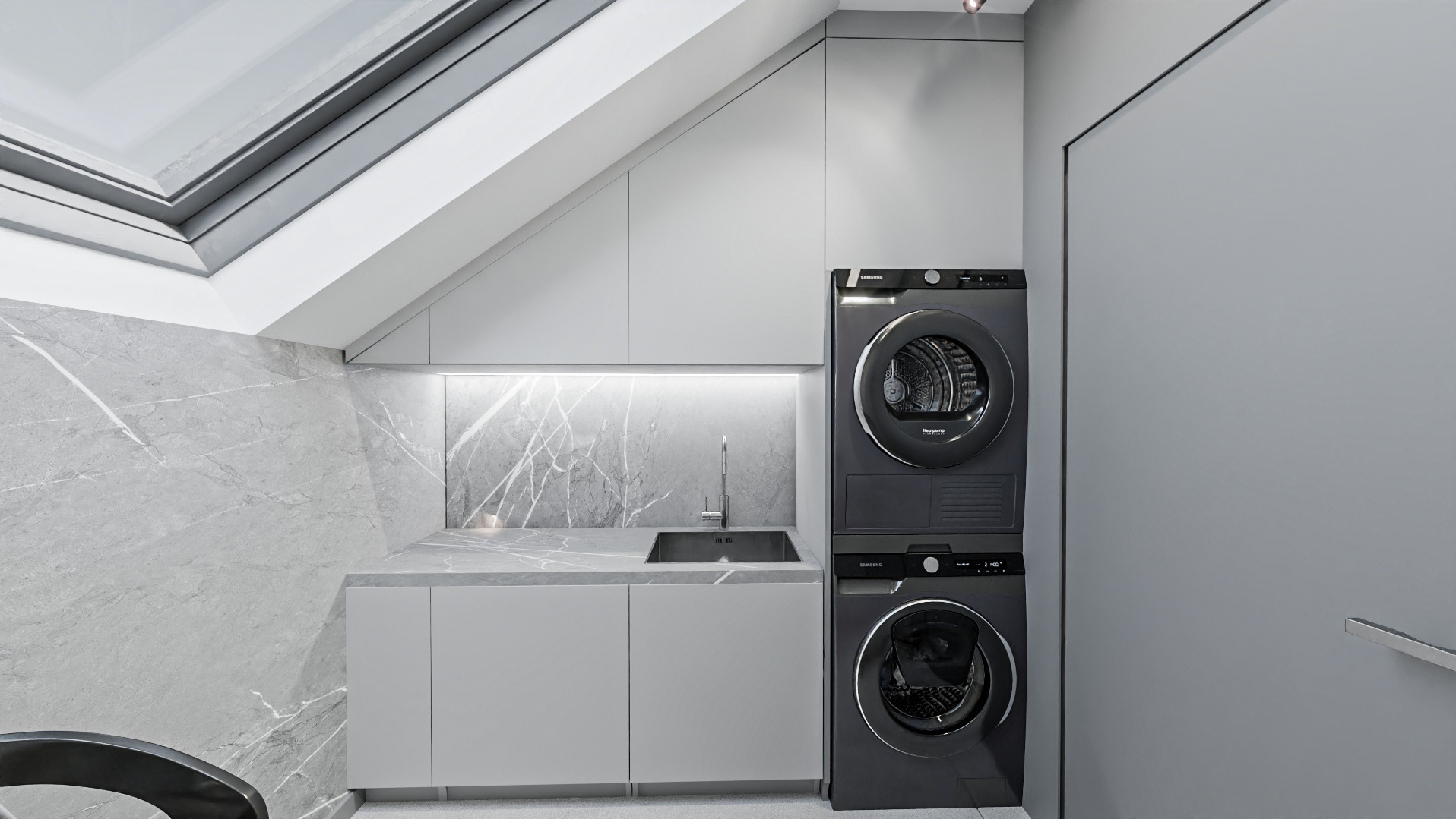 Szara łazienka na poddaszu ze skośnym oknem dachowym, marmurową ścianą i blatem, zintegrowanym zlewem oraz zestawem pralko-suszarki w kolorze grafitowym.