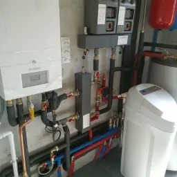 Kotłownia z piecem De Dietrich, zbiornikiem wyrównawczym, zmiękczaczem wody i licznymi rurami miedzianymi oraz z tworzyw sztucznych.