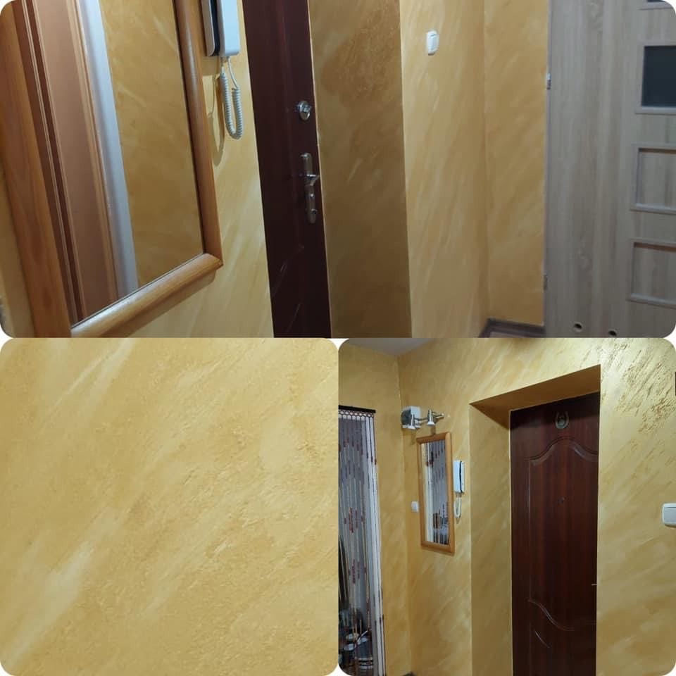 Korytarz po malowaniu ścian na żółto z efektem dekoracyjnym, widoczne drzwi wejściowe, lustro w drewnianej ramie i domofon.