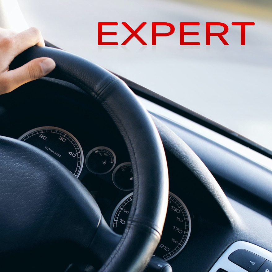 Dłoń na kierownicy samochodu, widoczny kokpit z prędkościomierzem i napisem 'EXPERT' na tle, potencjalnie instruktor jazdy w Tczewie.