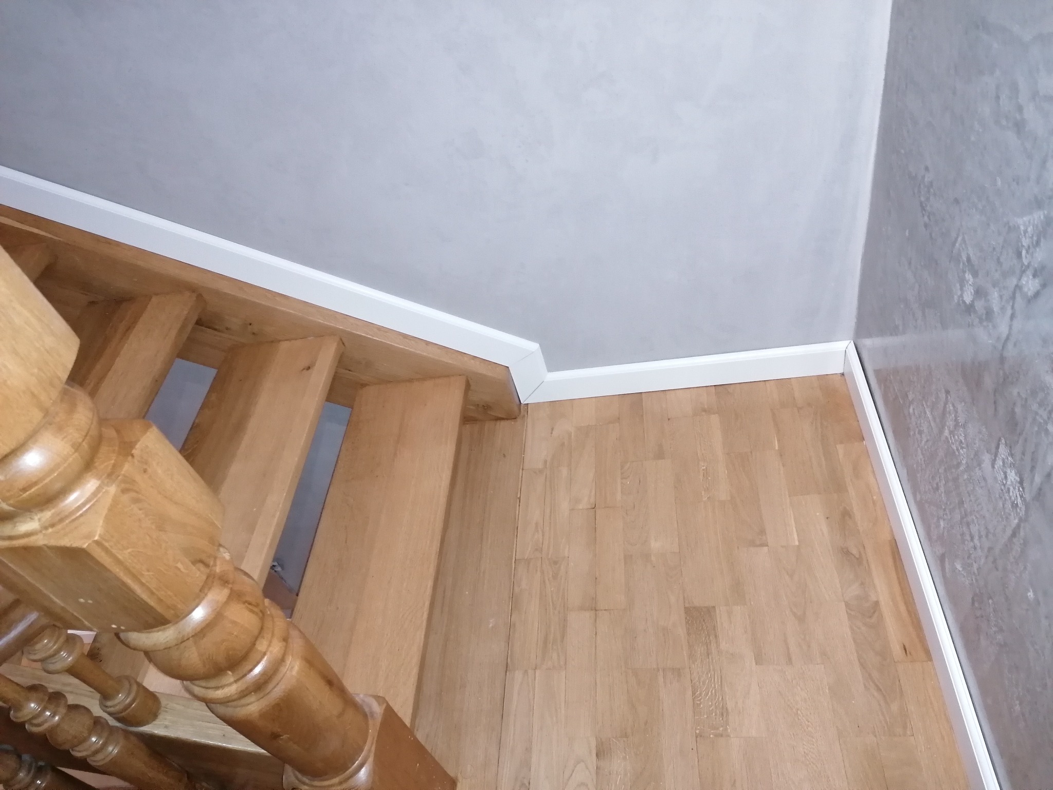 Fragment dębowych schodów z balustradą i podłogi wykończonej listwą przypodłogową, widok z góry.