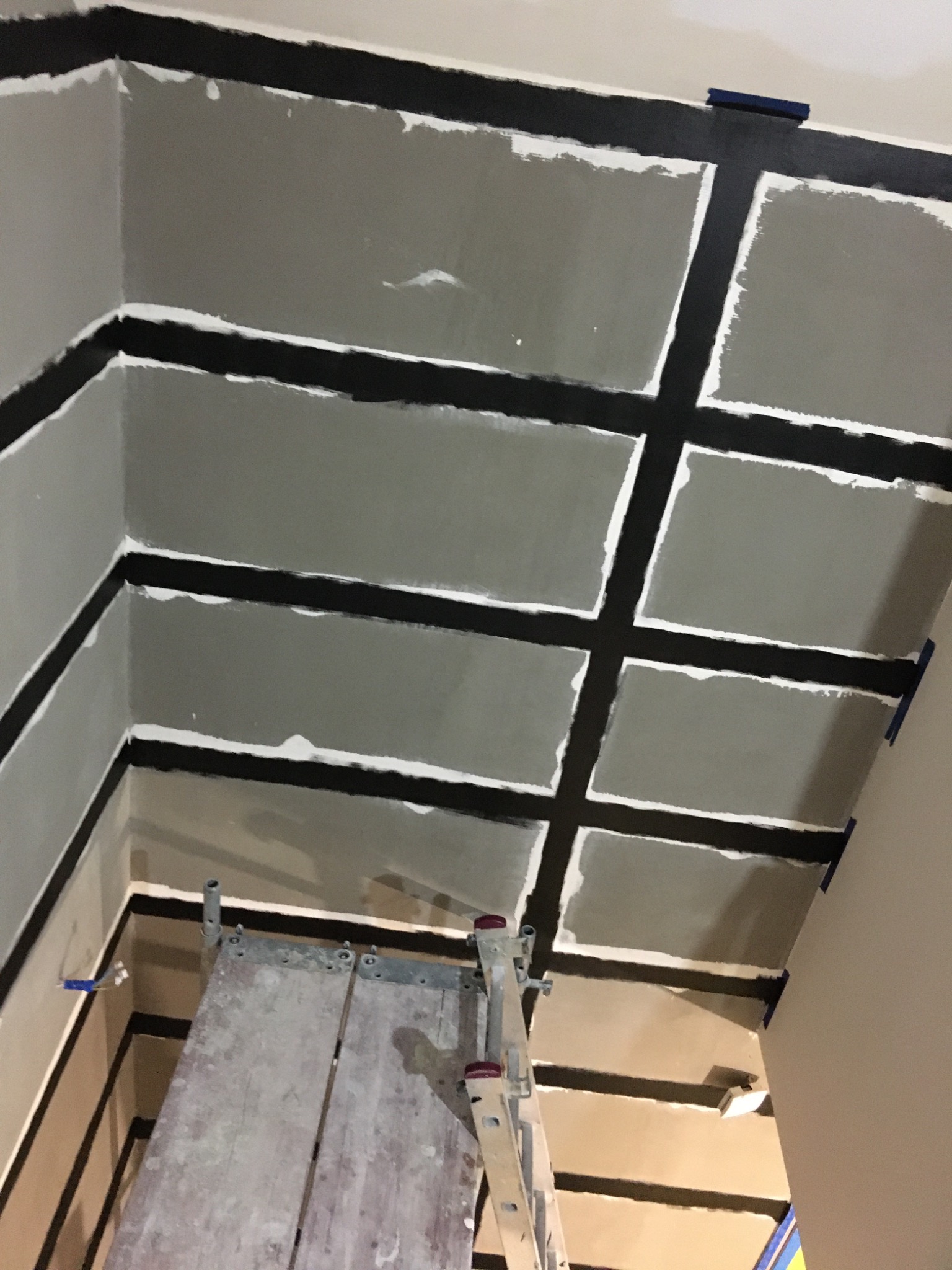 Sufit poddasza w trakcie montażu płyt kartonowo-gipsowych na konstrukcji z profili, widoczna drabina malarska i taśma malarska zabezpieczająca krawędzie.