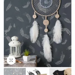 Dekoracja ścienna z motywem piór, ręcznie malowany wzór na ścianie, łapacz snów z piórami, lampion i roślina doniczkowa na drewnianym blacie tworzą spójną aranżację wnętrza.