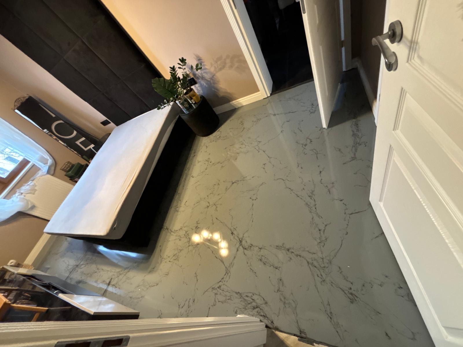 Jasnoszara podłoga z efektem marmuru w sypialni we Wrocławiu, widok z góry, obok drzwi wejściowych i łóżka.