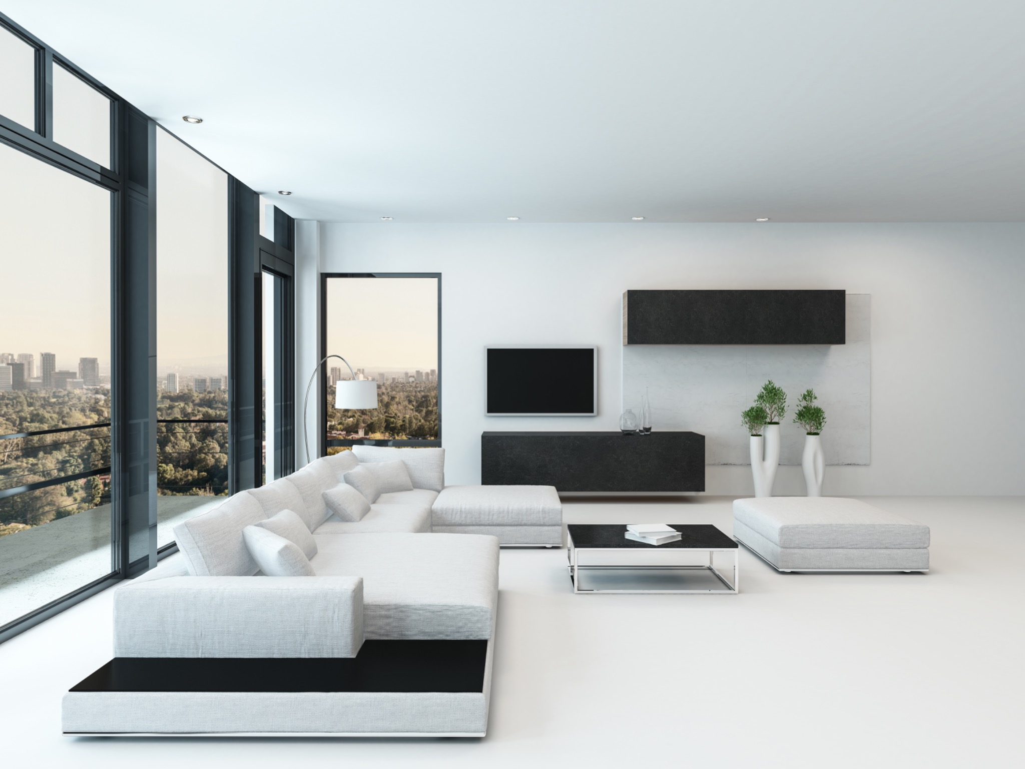 Minimalistyczne wnętrze z białym narożnikiem i widokiem na miasto przez panoramiczne okno, czarna podstawa sofy i stolika kawowego, biała podłoga.