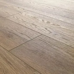 Jasnobrązowe panele podłogowe z wyraźnym rysunkiem słojów ułożone pod kątem, z widocznymi łączeniami na podłodze.