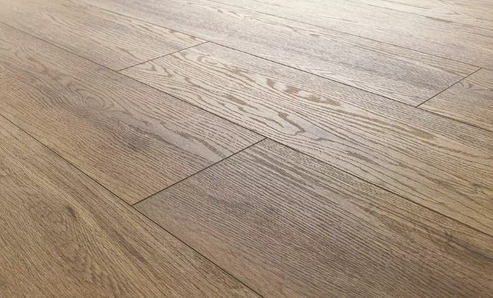 Jasnobrązowe panele podłogowe z wyraźnym rysunkiem słojów ułożone pod kątem, z widocznymi łączeniami na podłodze.
