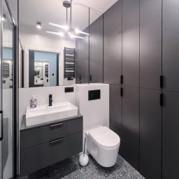 Patrycja Kucharek Studio10 - Nowoczesna łazienka z szarą zabudową meblową, umywalką nablatową, toaletą wiszącą i lustrem na całej ścianie, odbijającym wnętrze. Na podłodze terazzo.