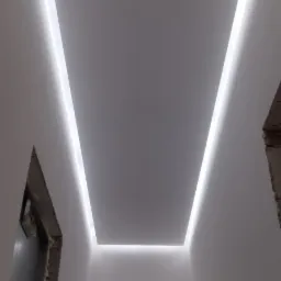 Nowoczesny sufit podwieszany z oświetleniem LED, widoczne niedokończone obramowania drzwi.