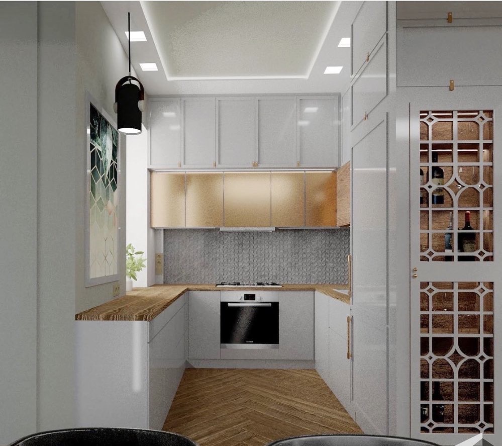 Nowoczesna kuchnia w odcieniach bieli i złota, z drewnianym blatem, szarą mozaiką na ścianie i ozdobną szafką na wino z geometrycznym wzorem.