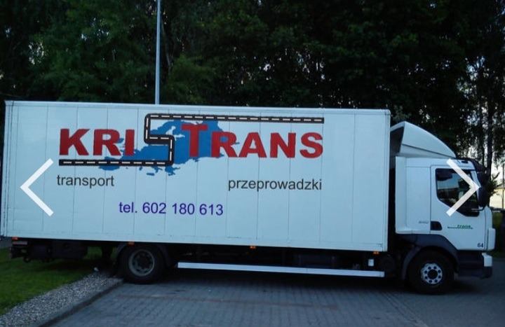 Biała ciężarówka z logo firmy transportowej KRI-TRANS, z numerem telefonu i informacją o transporcie i przeprowadzkach, na tle zieleni i kostki brukowej.