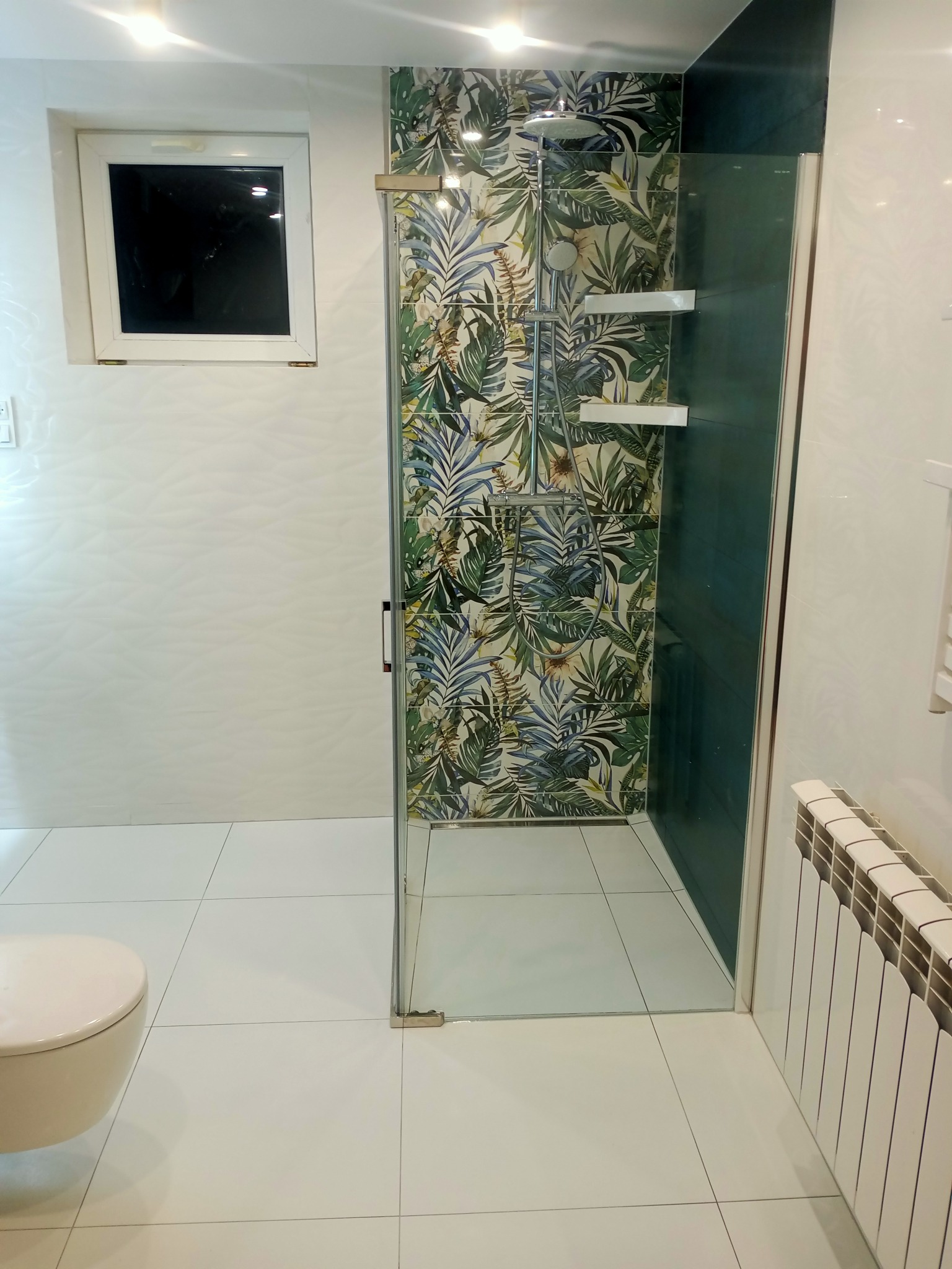 Wykończona łazienka w Piwodzie z kabiną prysznicową z motywem roślinnym, białymi płytkami i wiszącą toaletą.