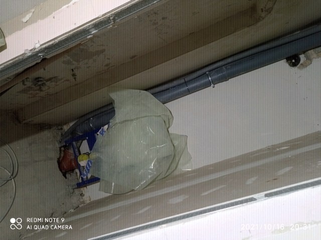 Montaż rur kanalizacyjnych pod sufitem podwieszanym, zabezpieczone folią malarską, widoczne elementy konstrukcji metalowej i fragment okna.