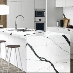 Nowoczesna kuchnia z białym blatem o marmurkowym wzorze Calacatta Ajaccio, wyspa kuchenna z trzema hokerami, drewniana podłoga i białe szafki.