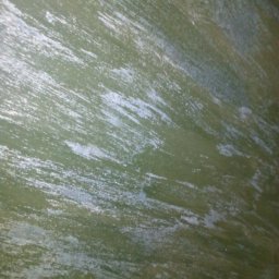 Gogobud - Ściana pomalowana na zielono z widocznymi pociągnięciami pędzla, tworzącymi efekt tekstury.