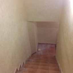 Gogobud - Klatka schodowa wykończona terakotą, ściany pokryte dekoracyjną, jasną farbą strukturalną, widok z góry.