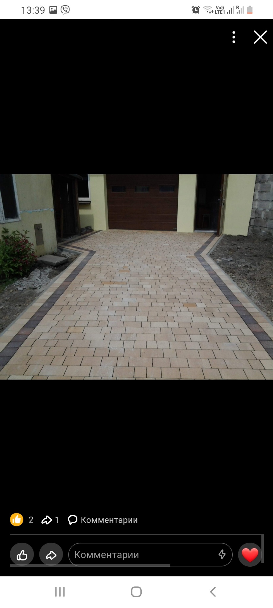 Nowo ułożony podjazd z jasnej kostki brukowej z obramowaniem z ciemniejszej kostki, prowadzący do garażu i drzwi wejściowych domu.