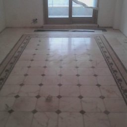 Mykola Haliiash - Ułożona marmurowa podłoga z dekoracyjnym bordiurem, widok na okno z rozwianą firanką, surowy stan wykończenia pomieszczenia.