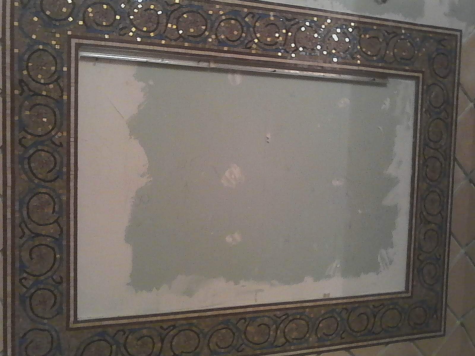 Przygotowanie ściany pod mozaikę w łazience, widoczne ślady po szpachlowaniu i dekoracyjna rama mozaikowa.