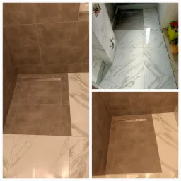 Układanie płytek w kabinie prysznicowej w Słupsku, widoczny odpływ liniowy i fragmenty płytek imitujących marmur.