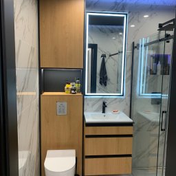 Zakład Stolarsko Budowlany HOLZ Rafał Bembnowicz - Nowoczesna łazienka z toaletą podwieszaną, szafką z umywalką i lustrem z podświetleniem LED, wykończona płytkami imitującymi marmur.