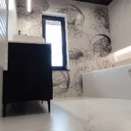 Nowoczesna łazienka z czarnym sufitem, białą marmurową podłogą i ścianą z motywem meduzy, minimalistyczna szafka pod umywalką i podświetlane lustro.