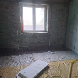Mateusz p - Wnętrze pokoju w trakcie remontu: surowe cegły, nowe okno z pomarańczowym uszczelnieniem, izolacja podłogi folią i styropianem. Widoczne ślady wcześniejszych prac.