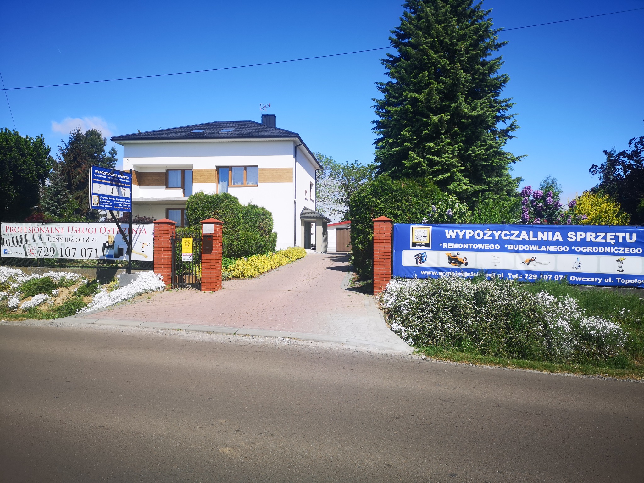 Firma oferująca usługi remontowe, budowlane i ogrodnicze w Owczarach, z widocznym banerem reklamowym i budynkiem biurowym w tle.