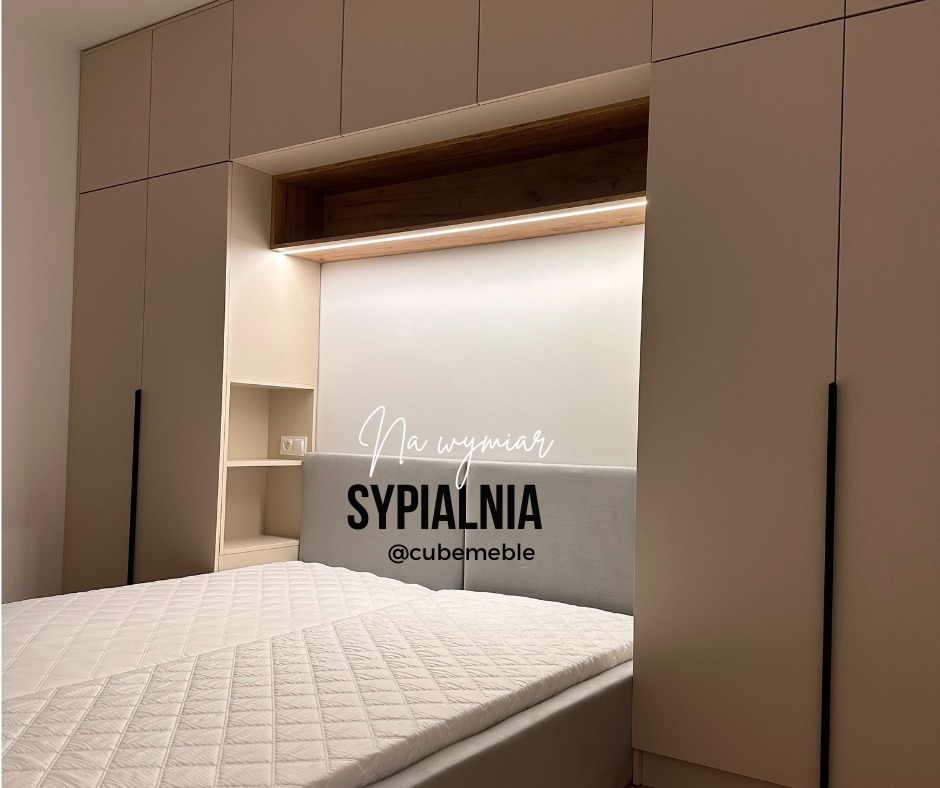 Sypialnia z łóżkiem i zabudową meblową na wymiar w odcieniach beżu i bieli, z podświetlaną wnęką nad wezgłowiem i czarnymi, minimalistycznymi uchwytami szaf.