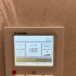 Smart Free Wind - Panel sterowania klimatyzacją Mitsubishi Heavy Industries ustawiony na 18 stopni Celsjusza, tryb chłodzenia, z widoczną informacją 'In operation for running'.