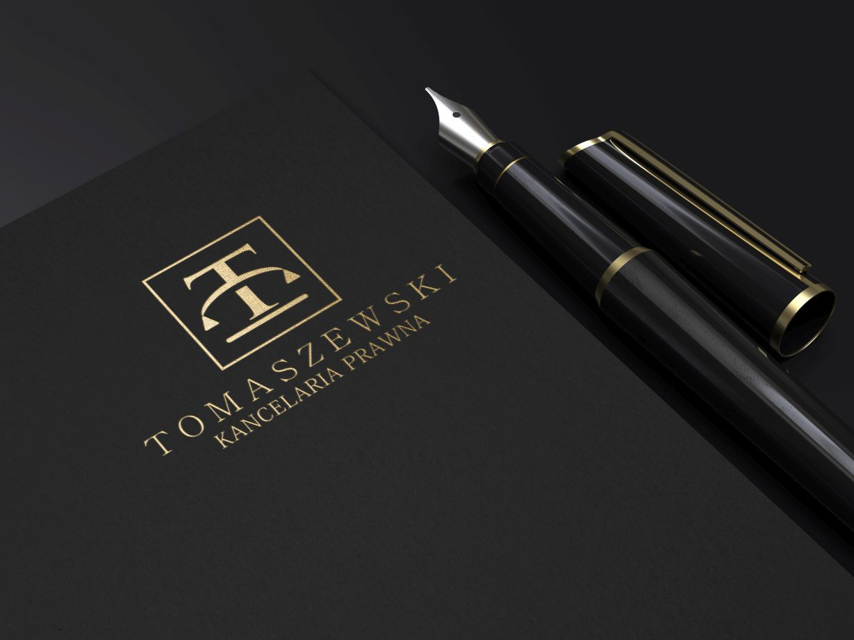Eleganckie, złote logo kancelarii prawnej Tomaszewski na czarnym papierze obok czarnego pióra wiecznego z elementami w kolorze złota, leżące na czarnym tle.