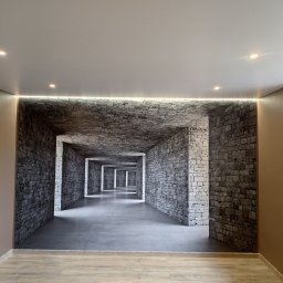 HTS Home&Apartment PARTNER - Pokój z fototapetą imitującą kamienny korytarz, oświetlony listwą LED pod sufitem napinanym z punktowymi lampami.
