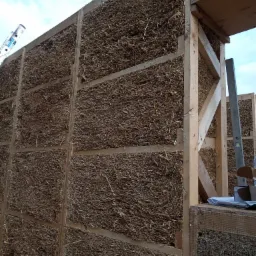 Konstrukcja domu ze słomy w Nysie, widoczne drewniane ramy wypełnione słomą, etap budowy.