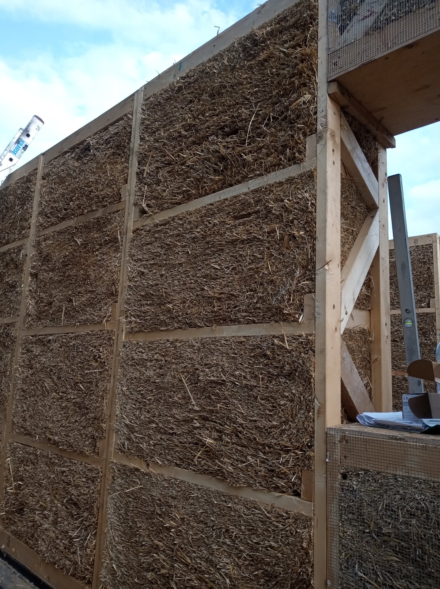 Konstrukcja domu ze słomy w Nysie, widoczne drewniane ramy wypełnione słomą, etap budowy.