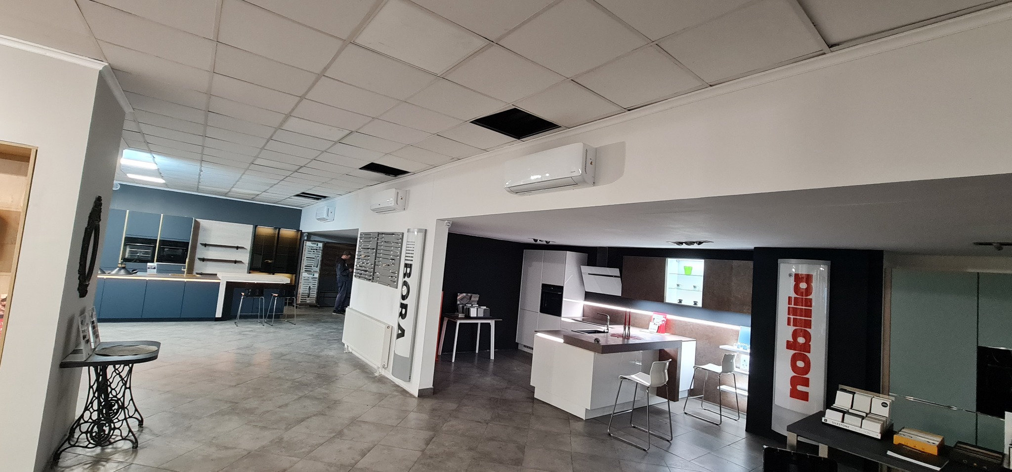 Salon z ekspozycją nowoczesnych kuchni, widoczne klimatyzatory na ścianie, ekspozytory marek Bora i Nobilia.