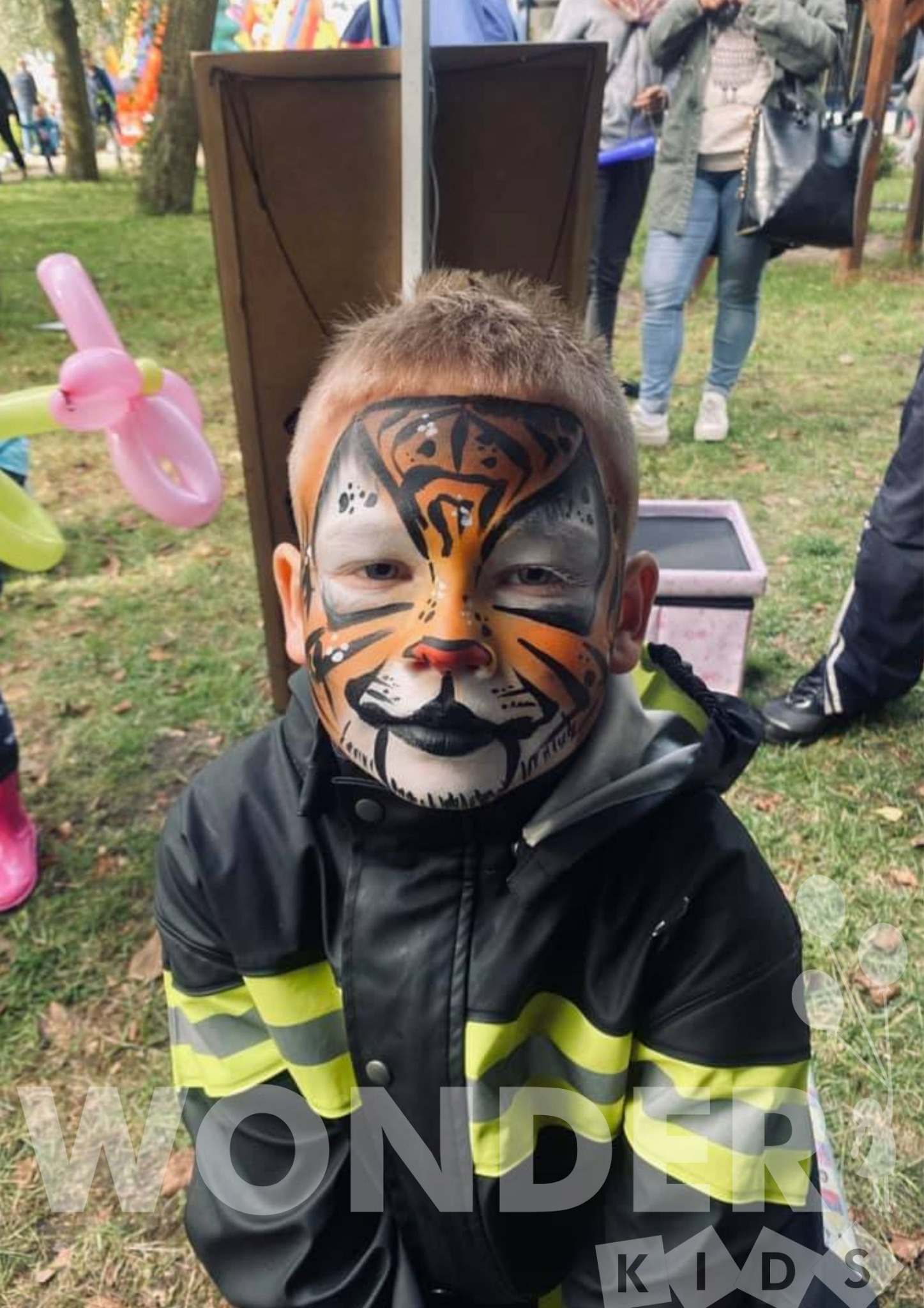 Chłopiec ze starannie wykonanym malunkiem na twarzy, imitującym tygrysa, w Szczecinie. W tle widoczne dekoracje balonowe.