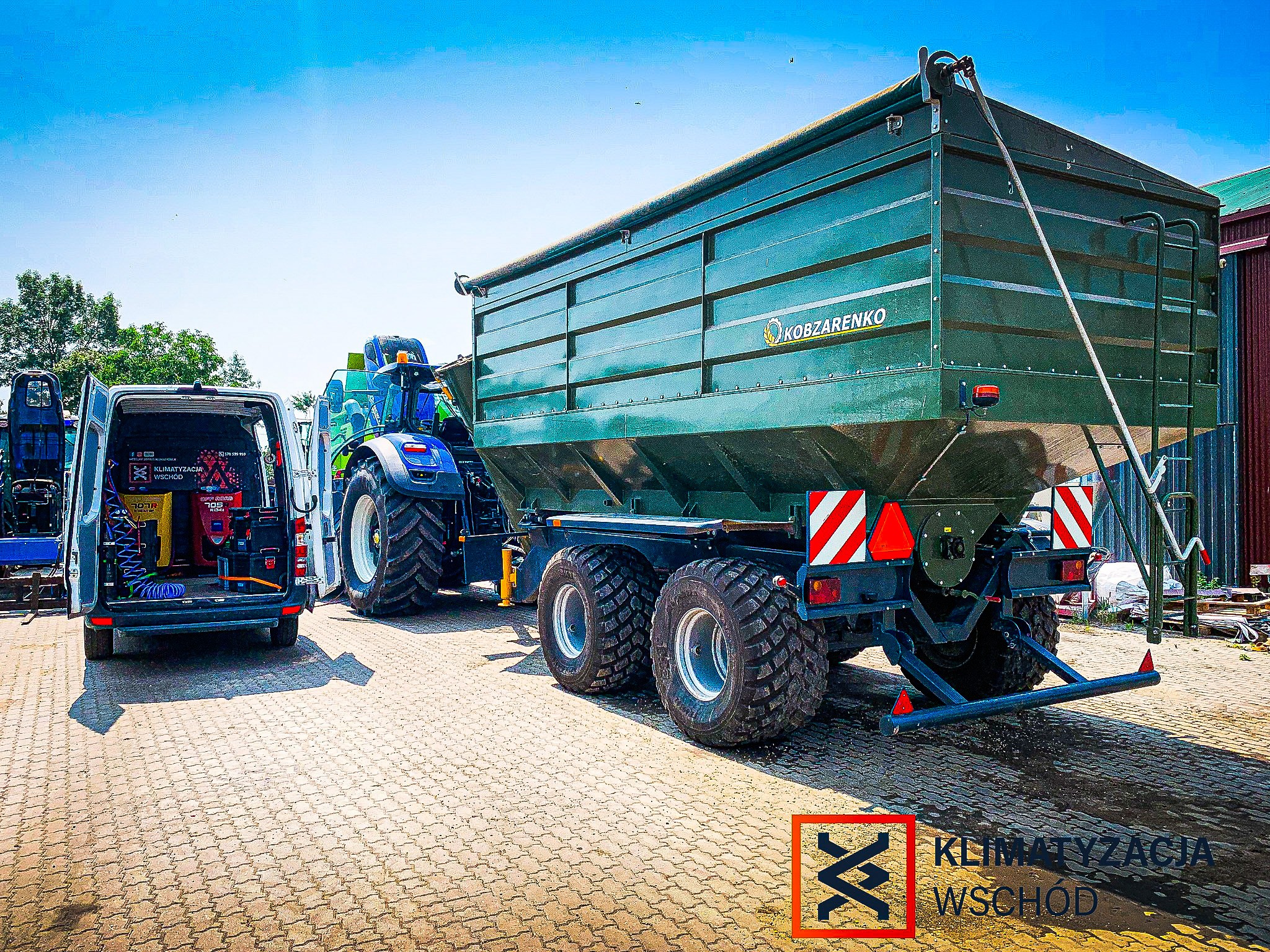 Serwis klimatyzacji mobilnej przy ciągniku rolniczym z przyczepą. Widoczny bus serwisowy z otwartymi drzwiami i sprzętem do naprawy klimatyzacji.