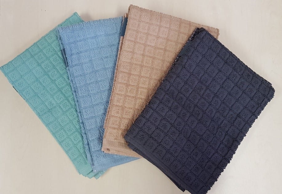 Cztery złożone ręczniki w odcieniach turkusu, błękitu, beżu i granatu, ułożone kaskadowo na białym tle, prezentujące wzór w drobną kratkę.