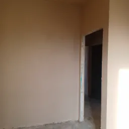 Świeżo otynkowane wnętrze z widocznym otworem drzwiowym w stanie surowym, przed wykończeniem podłóg i montażem ościeżnic.