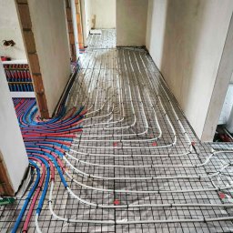 OliArt Instalacje Oleksandr Shram - Rozłożona instalacja ogrzewania podłogowego na folii izolacyjnej, rury białe i kolorowe, widok z góry, przygotowanie do wylewki, wnętrze w stanie surowym.