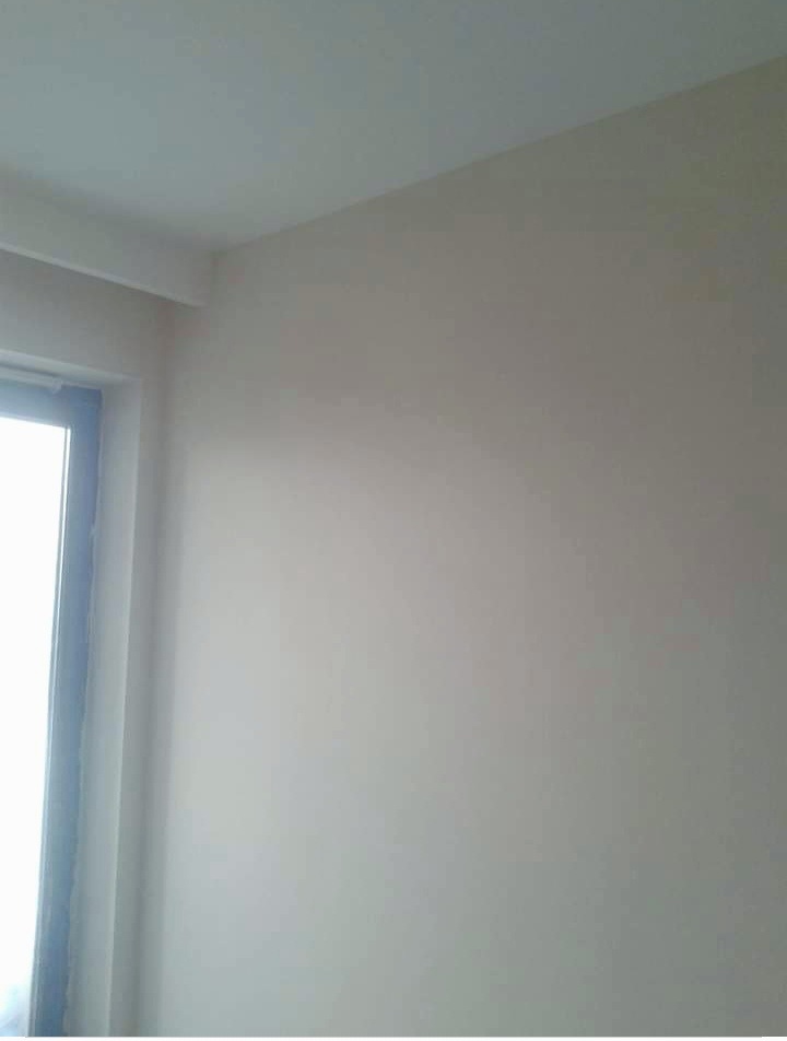Świeżo pomalowany narożnik pokoju w odcieniach beżu, widoczne subtelne przejścia tonalne i listwa przyokienna.