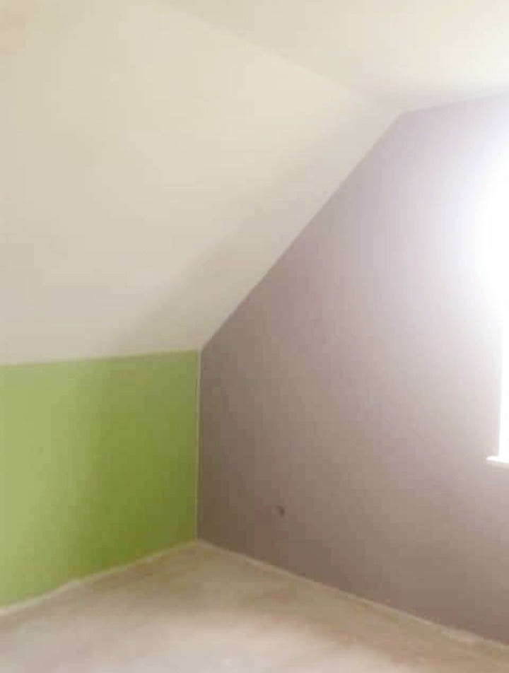 Pokój na poddaszu po malowaniu ścian na trzy kolory: biały sufit, oliwkowa dolna część ściany, fioletowa skośna ściana przy oknie.