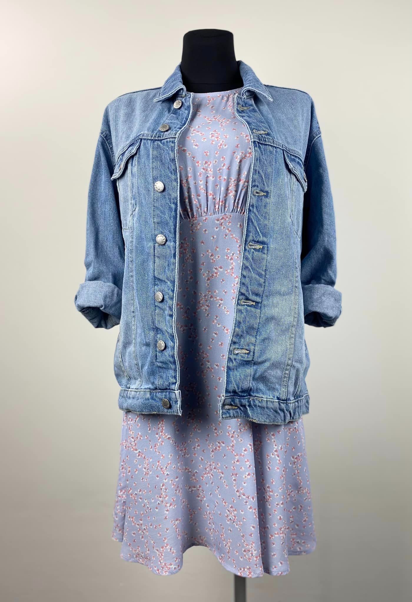 Jasnoniebieska sukienka w drobne kwiatki z dżinsową kurtką na manekinie, rękawy kurtki podwinięte.