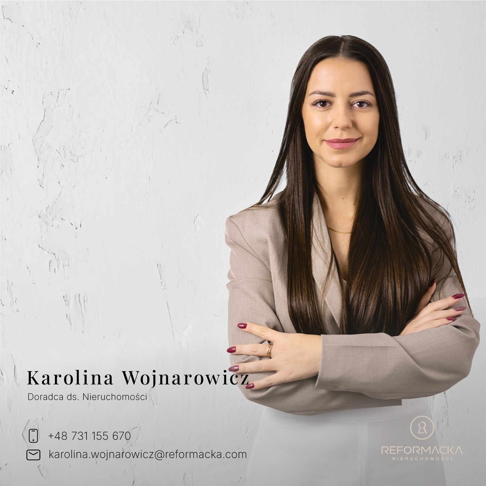 Portret uśmiechniętej kobiety, doradca ds. nieruchomości Karolina Wojnarowicz, z założonymi rękami, na tle jasnej ściany z delikatną fakturą.