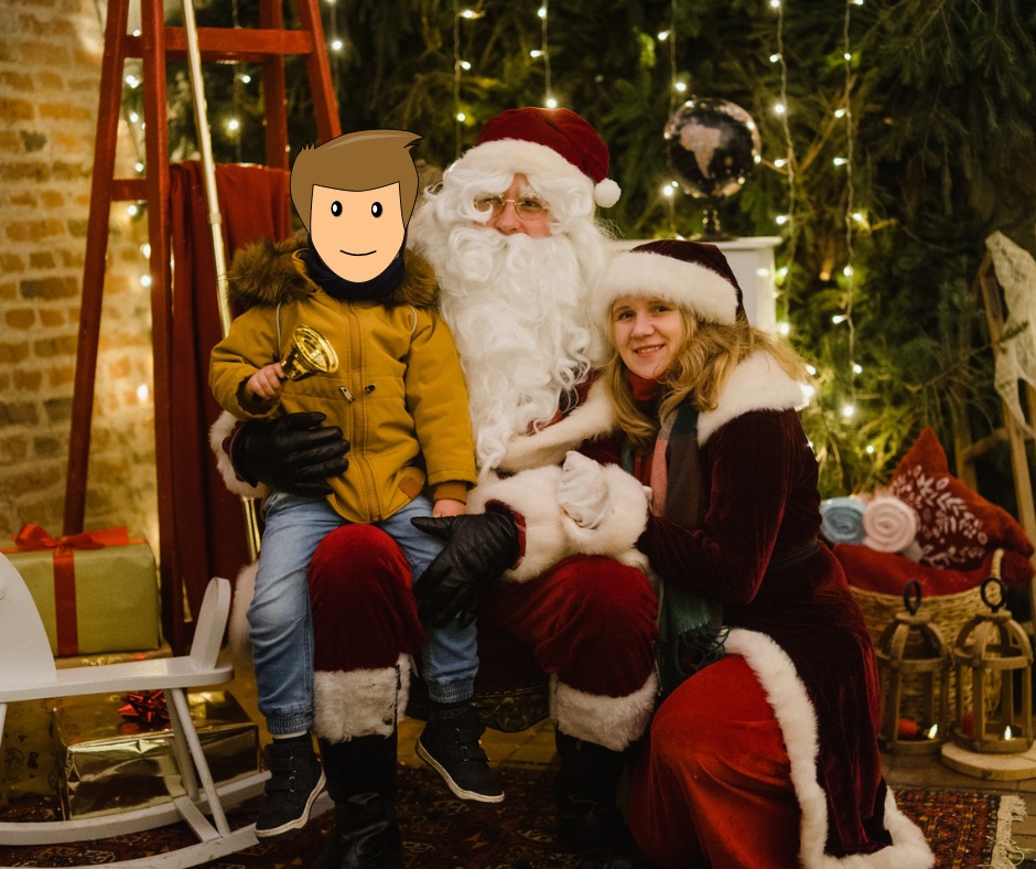 Święty Mikołaj z panią Mikołajową i dzieckiem z zamazaną twarzą trzymającym złoty dzwonek, siedzą na kolanach Mikołaja, na tle dekoracji świątecznych i światełek.