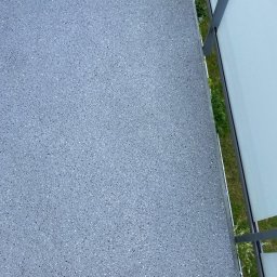 Woodstrug - Szara, drobnoziarnista powierzchnia balkonu z metalową barierką i widokiem na zieleń w tle.