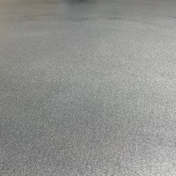 Woodstrug - Jasnoszara, gładka posadzka z efektem delikatnego metalicznego połysku, widoczna z bliskiej perspektywy, oświetlona z góry.