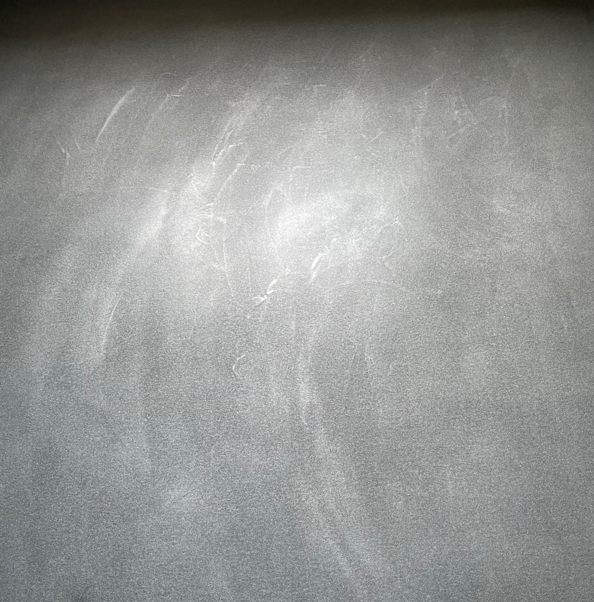 Szara powierzchnia z efektem chmurkowania i delikatnymi, jaśniejszymi smugami, przypominająca polerowany beton lub tynk dekoracyjny.