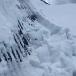 Śnieg zalega na dachu budynku z widocznymi fragmentami konstrukcji i śladami odśnieżania, pochmurne niebo w tle.